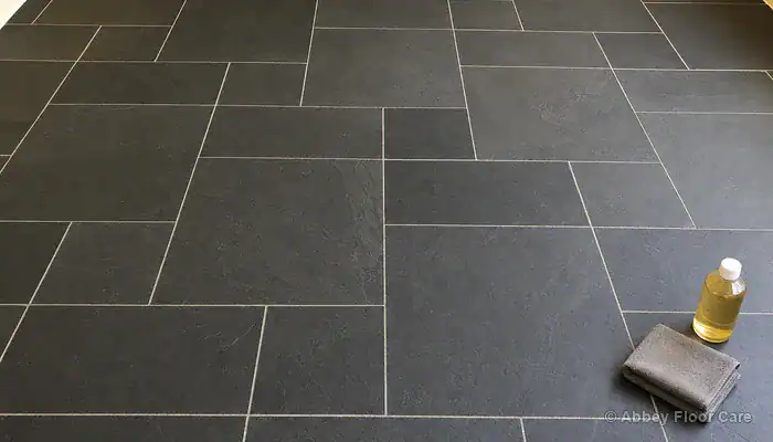 Clean dry riven slate floor with impregnating sealer and microfibre cloth placed ready for application
